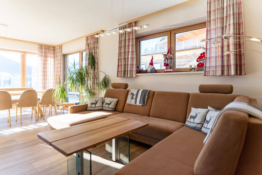Warm, modern living room with a beige sofa, wooden coffee table and leafy artwork